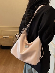 Glossy light pink tote bag with baseball charm shown from a model side view