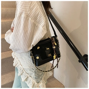 Detail of black glossy tote bag with gold pet charms, chain strap and knotted tassel