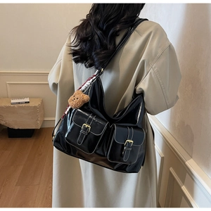 Détail du grand sac cabas noir brillant avec surpiqûres blanches et boucles dorées