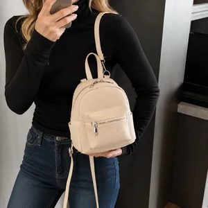 Close-up of beige mini backpack with woven texture and silver metal zipper detail