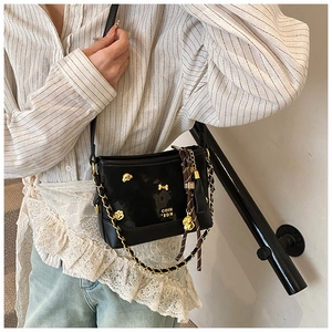 Close-up of black glossy tote bag with gold chain and bone-shaped hardware detail