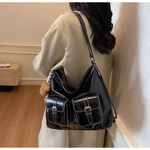 Détail du sac porté épaule noir brillant avec surpiqûres blanches et ours peluche