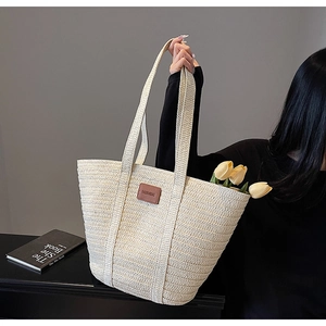 Detail of a large woven tote bag featuring a leather fashion tag and rustic texture