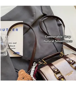 Dettaglio borsa retrò beige e marrone con ciondolo a forma di orsetto e finiture dorate
