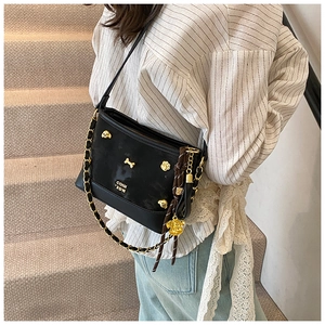 Close-up of black leather tote bag with gold dog-shaped hardware and metal chain strap