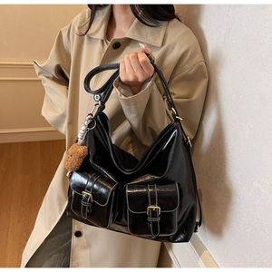 Détail du sac noir brillant avec surpiqûres blanches et poches à boucles dorées
