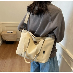 Back view of model wearing off-white canvas tote bag showing its large size and capacity