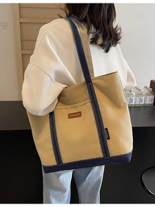 Large beige canvas tote bag with navy blue trim and shoulder straps for daily use