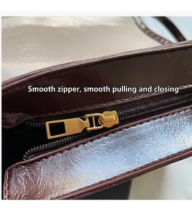 Dettaglio della cerniera dorata e della texture in pelle marrone scuro della borsa