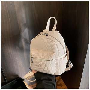 Close-up of beige mini backpack featuring woven texture and silver metal zippers
