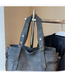 Close-up of dark grey tote bag featuring decorative rivets and a side zipper pocket