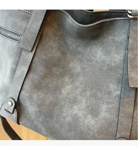 Close-up of grey matte suede tote bag featuring side metal zipper and reinforced seams