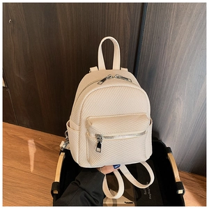 Close-up of beige mini backpack featuring woven texture and double zipper compartments