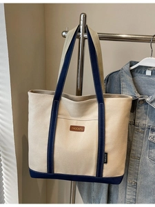 Minimalist canvas tote bag with deep blue straps and brown leather brand tag