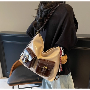 Gros plan sur un sac hobo beige avec poches brunes et breloque ours en peluche