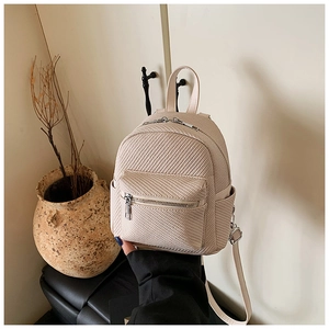 Detailed macro view of beige mini backpack with woven texture and silver hardware details