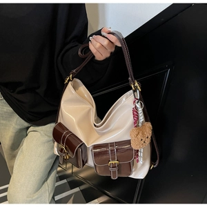 Détail du sac à main crème et marron avec boucles métalliques et un petit ours en peluche
