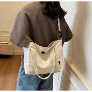 Close-up of beige canvas tote with long shoulder strap and circular detail decoration