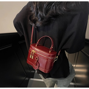 Detailansicht der burgunderroten Zylindertasche aus Leder mit goldenem Reißverschluss