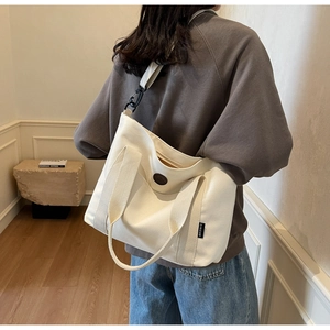 Rear view of model wearing a beige canvas tote bag with adjustable shoulder straps