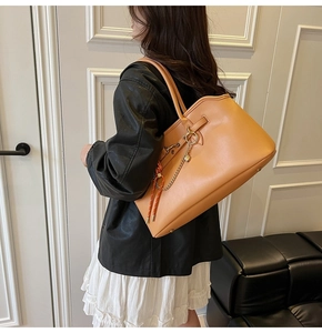 Detailed view of large leather tote bag with heart charm and golden chain detail