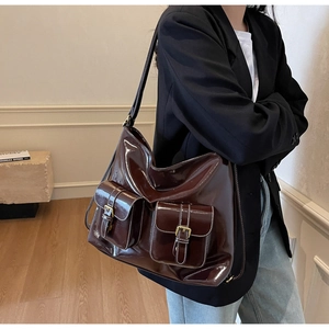 Détail d'un grand sac à bandoulière en cuir ciré marron avec boucles rétro sur les poches