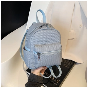 Side view of light blue mini backpack with woven texture and silver zippers on white suit