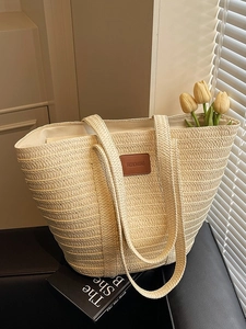 Large woven straw tote bag with leather patch and long handles for beach vacations