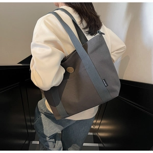 Detail of dark grey canvas tote bag with contrast straps and vintage leather logo patch