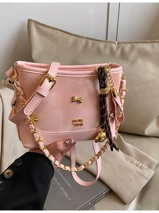 Pink leather tote bag with gold bone hardware and chain strap on neutral lifestyle background