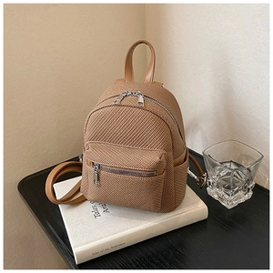 Detail of a brown woven mini backpack with silver zippers and synthetic leather trim