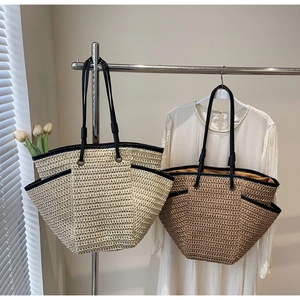 Detail of handwoven straw bags in cream and tan with black leather trim and handles