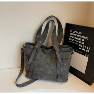 Detailed view of retro grey-green tote bag featuring weathered leather texture and zips
