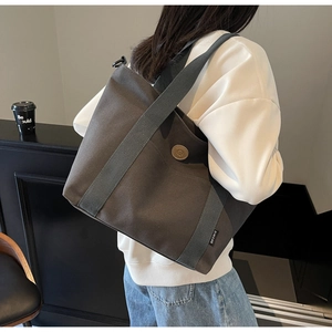 Detail of dark grey canvas tote bag featuring reinforced strap and vintage round badge