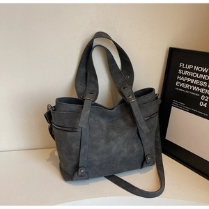 Detail of dark grey faux suede tote bag featuring rivet decor and functional side zipper