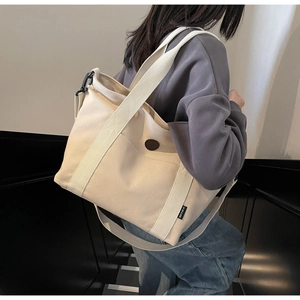 Macro view of large canvas tote bag showing wide shoulder strap and durable fabric detail