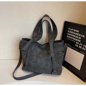 Detail of dark grey tote bag featuring matte texture, metal rivets and bronze hardware