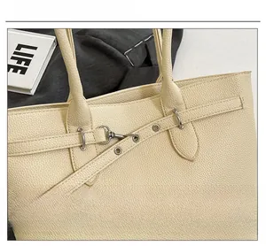 Gros plan d'un sac cabas beige en cuir grainé avec détails métalliques et surpiqûres
