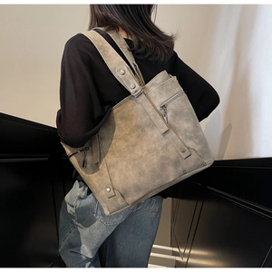 Close-up of taupe tote bag with side zipper detail and textured vintage finish