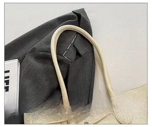 Détail des bandoulières arrondies confortables sur un sac cabas en cuir beige