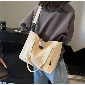 Detail of large beige canvas tote bag with adjustable shoulder strap and reinforced handles