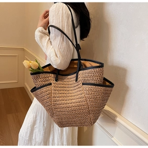 Close-up of woven straw tote bag with black leather trim and side pocket detail