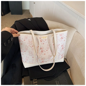 Detailansicht einer weißen Tragetasche mit rosa Comic-Prints und goldenem Markenlogo