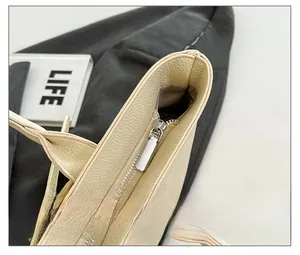 Détail de la fermeture éclair en métal argenté et du cuir crème texturé du sac cabas