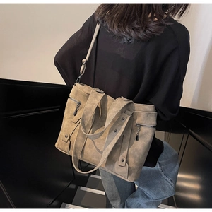 Detail of khaki suede tote bag showing zipper pockets and adjustable shoulder strap
