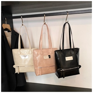 Detailed view of three glossy faux leather tote bags with metal plaques and zippers