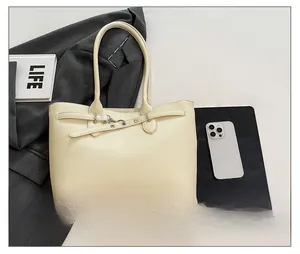 Détail du sac cabas en cuir crème avec boucles argentées dans un décor de bureau