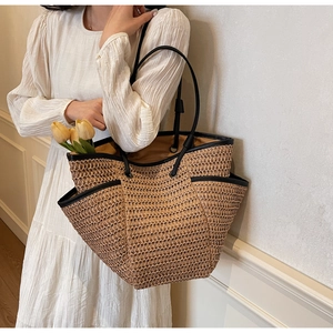Close-up of woven straw tote bag with black trim detailing and side pocket feature