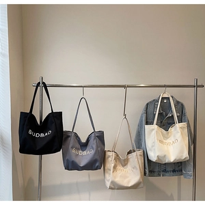 Detail view of canvas tote bags in four colors with BUDBAO embroidery on simple hangars
