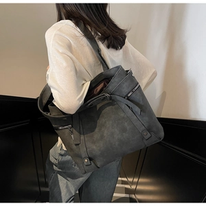 Detail of dark grey tote bag with rivets and decorative zippers in a lifestyle setting